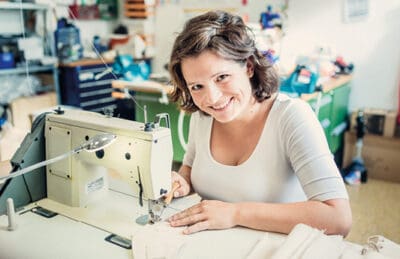 Eine Frau sitzt an einer Nähmaschine in ihrer Nähstube